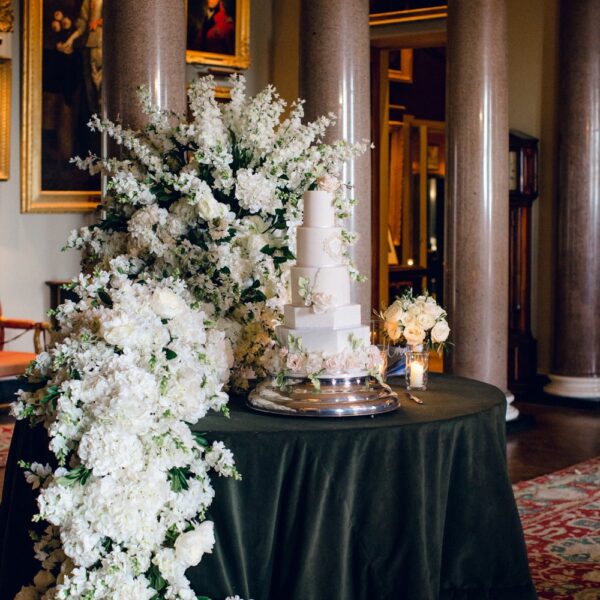 The front hall at Goodwood house. Set up with the wedding cake and an impressive white floral backdrop installation by Paula Rooney