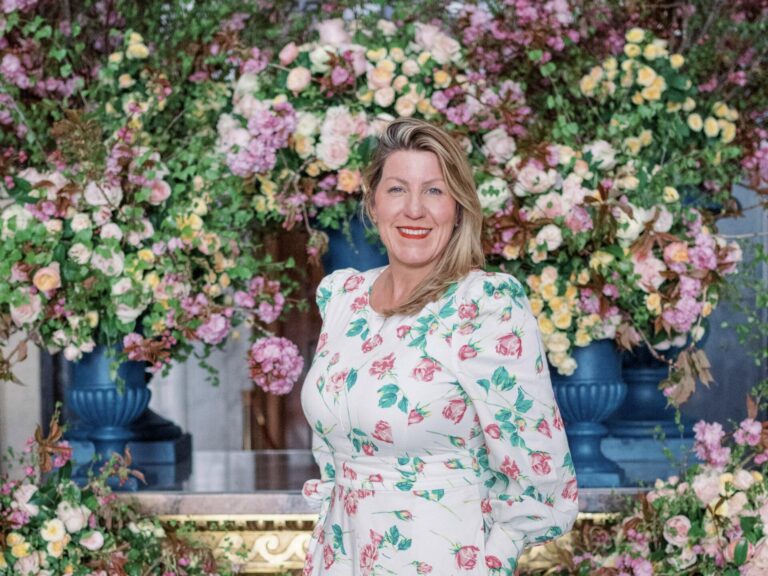 Luxury wedding and events florist and floral mentor, Paula Rooney, wearing a white dress standing in front of a colourful floral installation